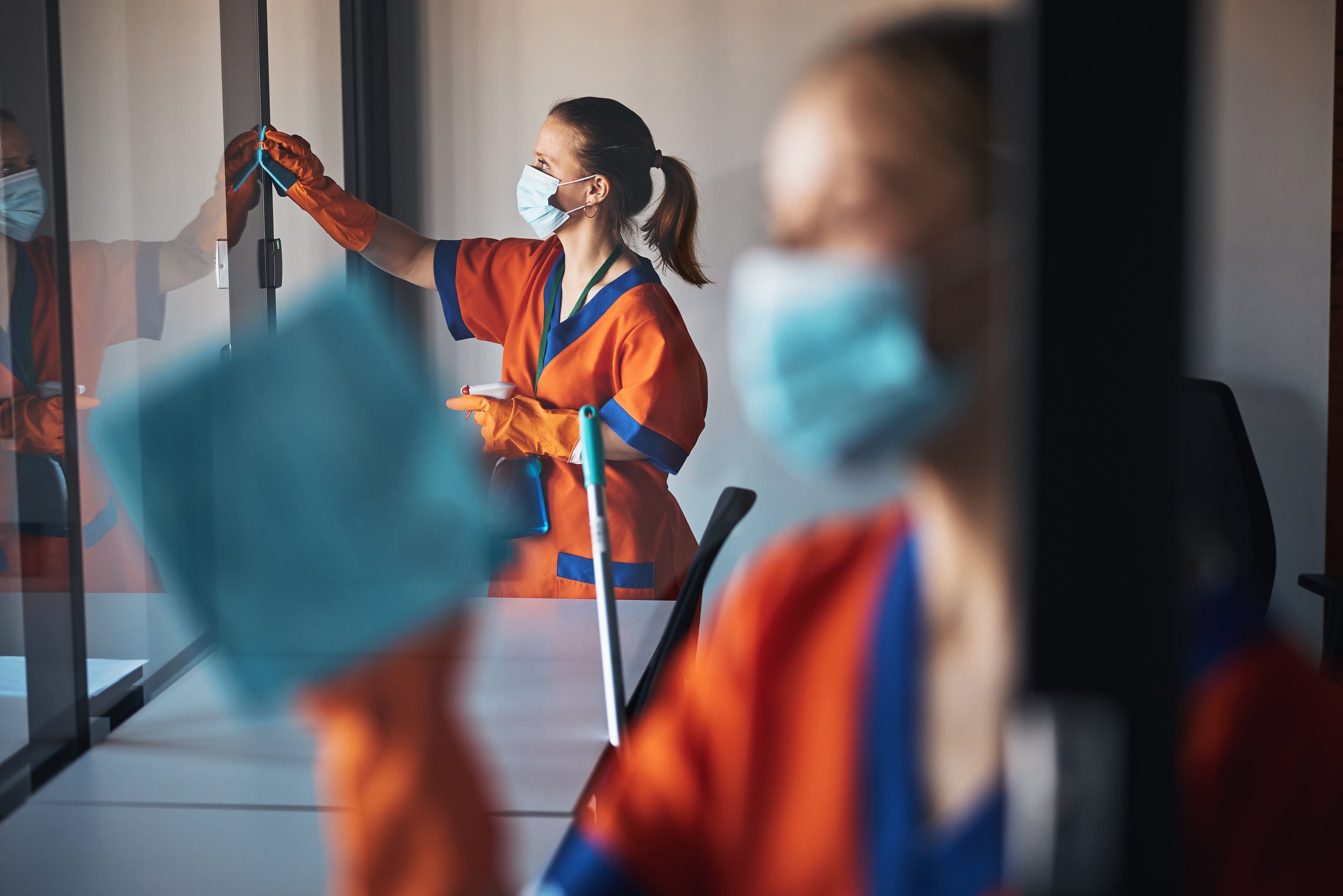A woman in an orange and blue uniform cleaning.
