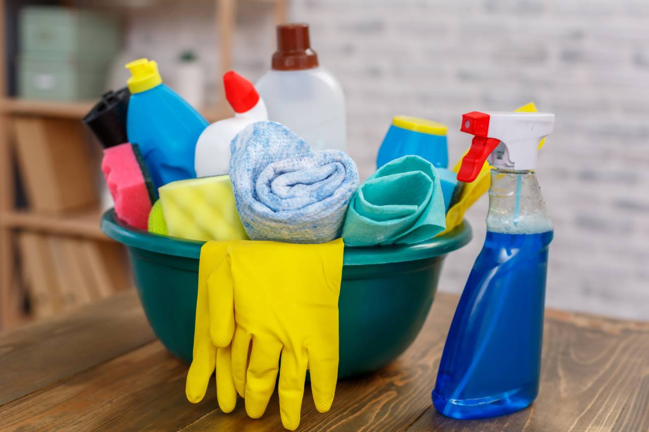 A bowl of cleaning supplies and gloves on the table.