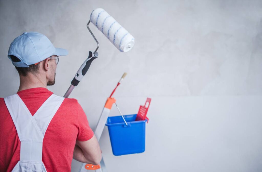 A man holding a paint roller and bucket.