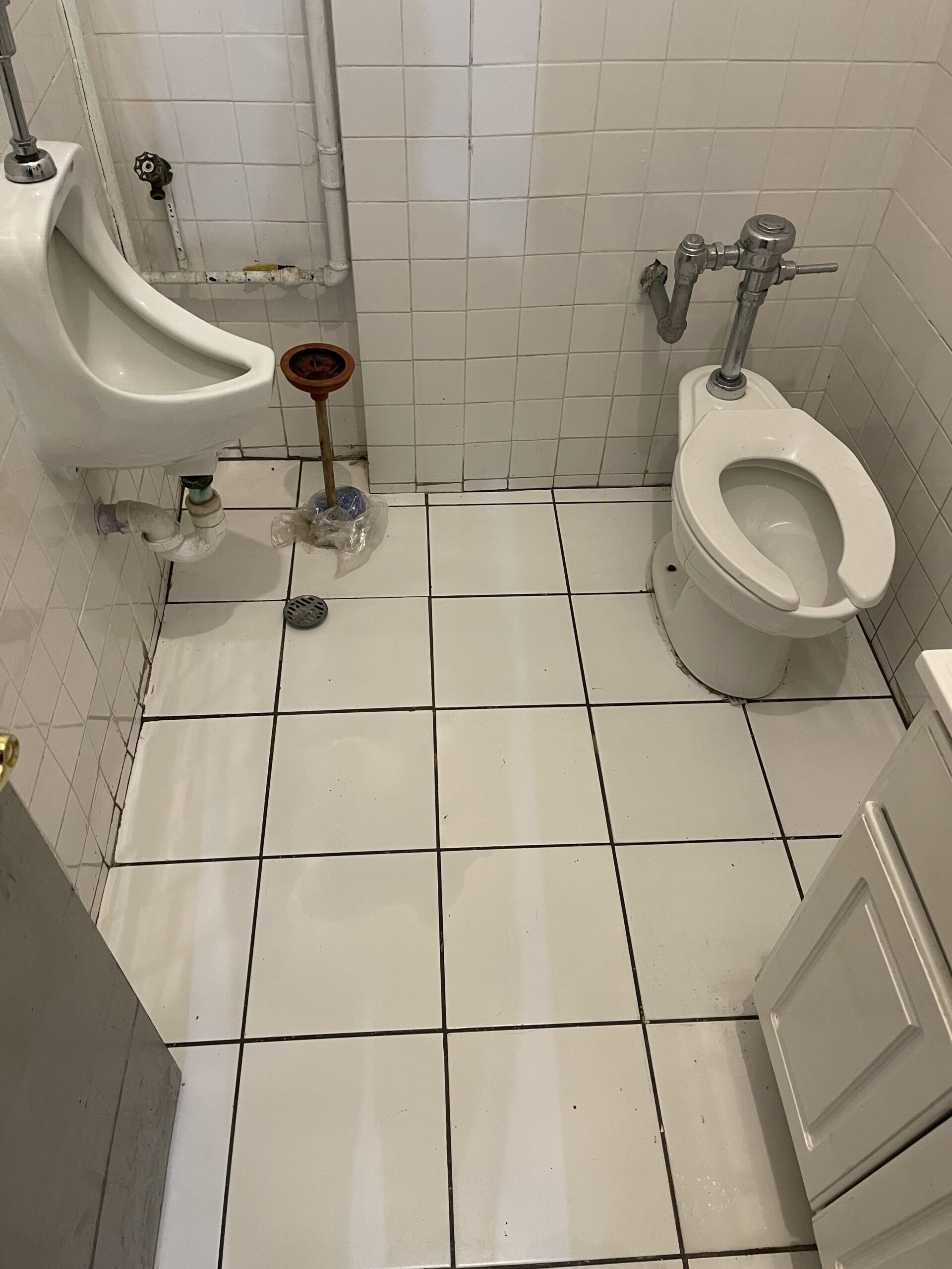 A bathroom with white tile and tiled floors.