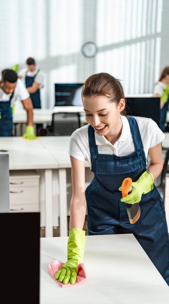 A woman in blue overalls cleaning the counter.