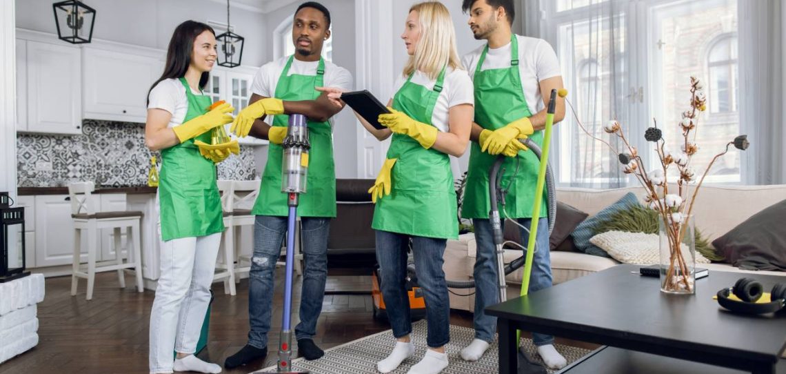 A group of people in green aprons and yellow gloves.